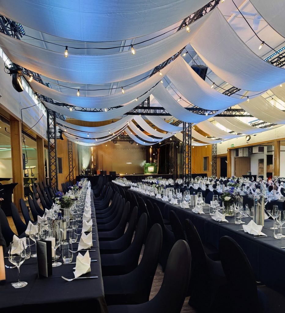 Festlich gedeckter Gala-Saal für eine Firmenveranstaltung mit Bühne für Eventband und Partyband