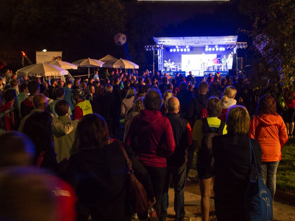 Großes Publikum versammelt sich vor einer Outdoor-Bühne bei einem Showact von Music Nau Now